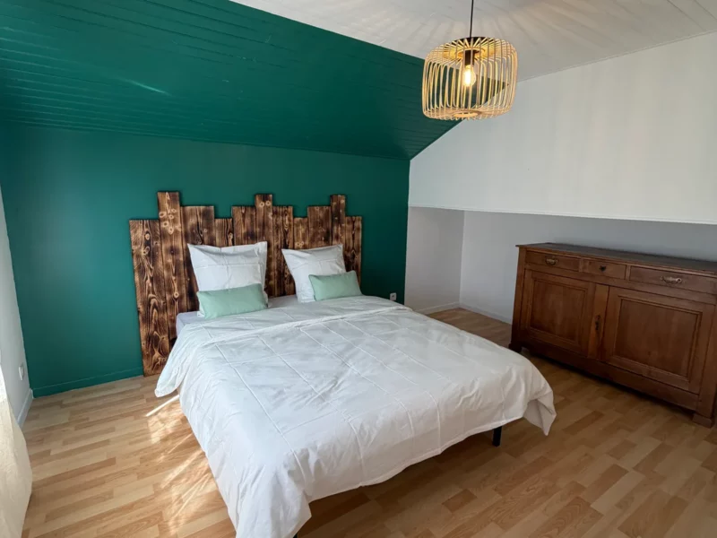 Chambre du Training Lodge, mur vert forêt et tête de lit en bois brûlé