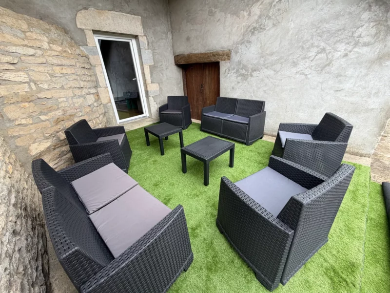 Terrasse extérieure en pierre du Training Lodge avec salon de jardin