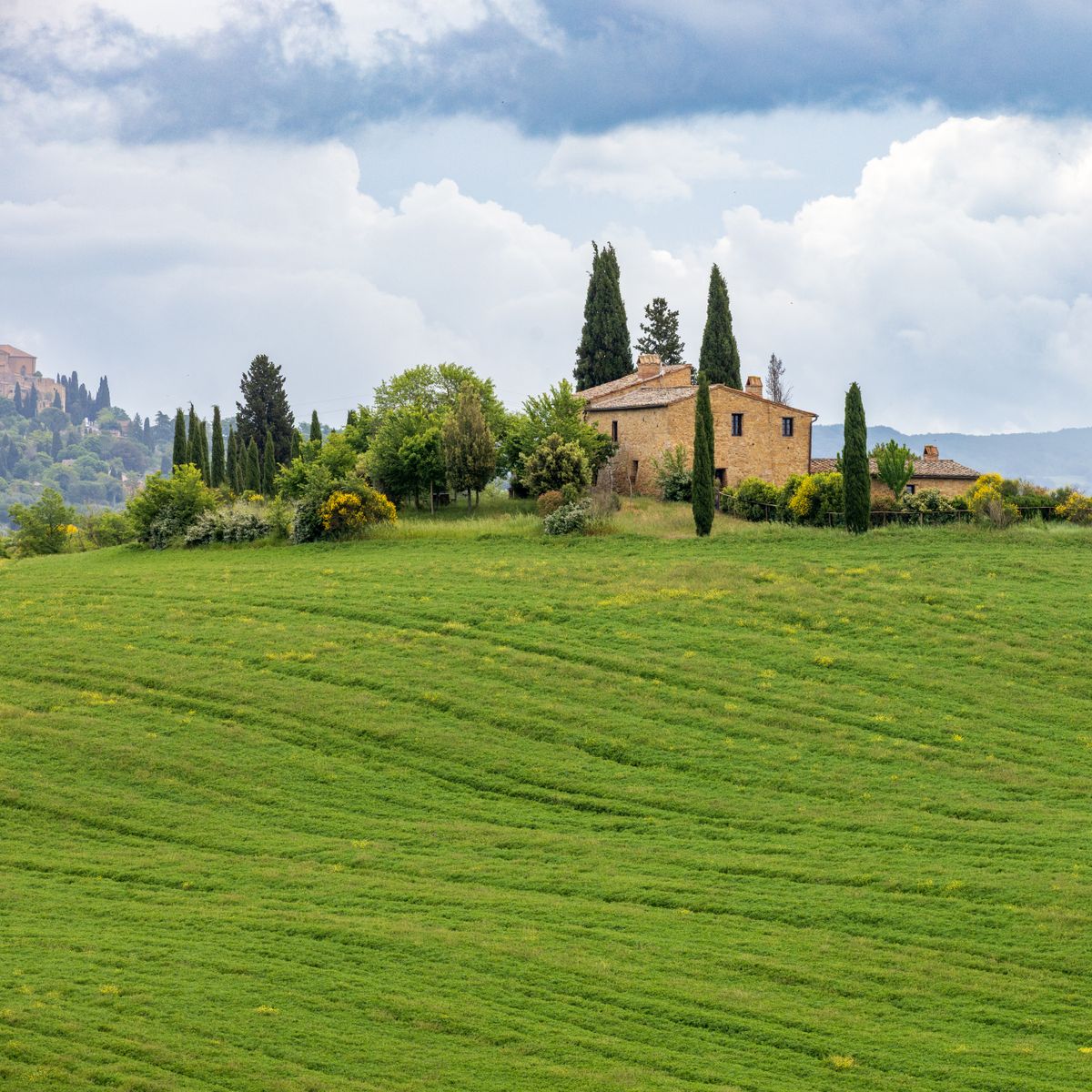 Maison de campagne rustique en pierre au milieu de collines et de cyprès à la tombée du jour